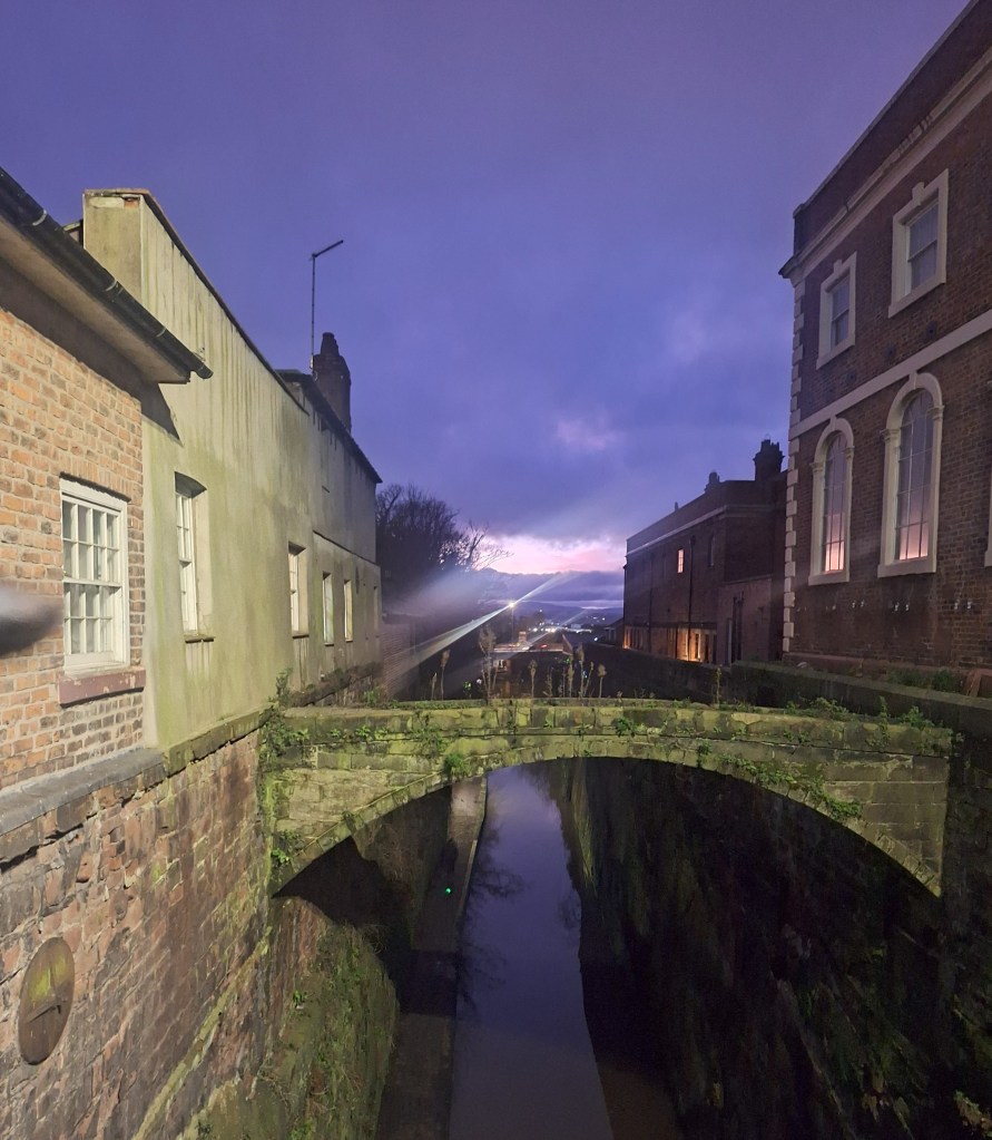 A footbridge between two buildings in Chester over a canal.